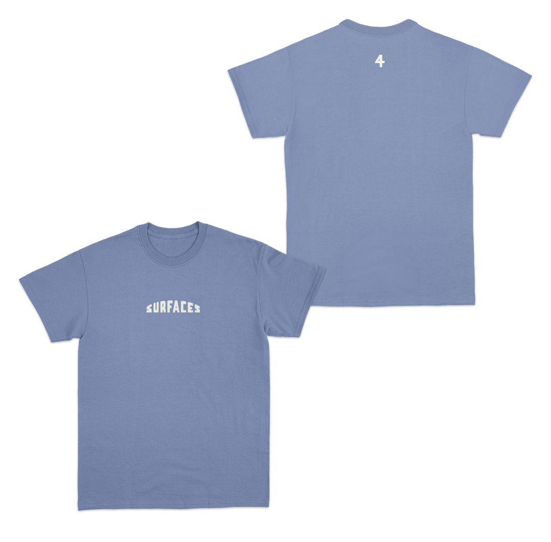 Blue t-shirt with the word "Surfaces" embroidered on the front center. The number 4 is printed small on the back just beneath the collar.